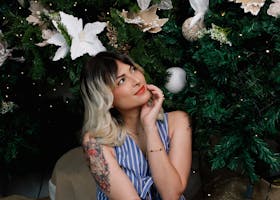 Smiling woman with floral tattoo enjoying Christmas holiday decorations in São Paulo.